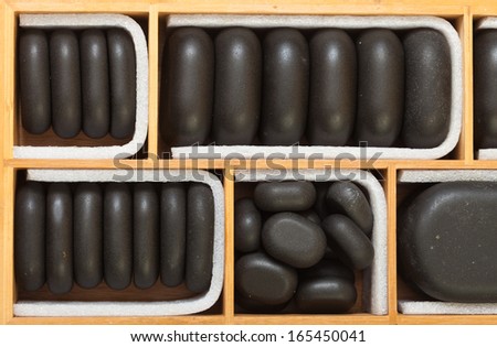 Beauty salon. Close up of black spa zen massage stones in wooden case as background. Relax concept.