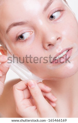 Portrait of blond girl young woman in facial peel off mask. Peeling. Beauty and body skin care. Isolated on white. Studio shot.