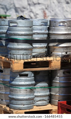 Lots of metal barrels beer kegs on the wooden palettes at factory brewery