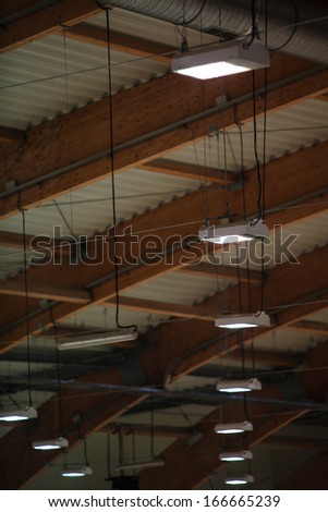 Group of electric lamps on sport stadium celling indoor. Light power and energy.