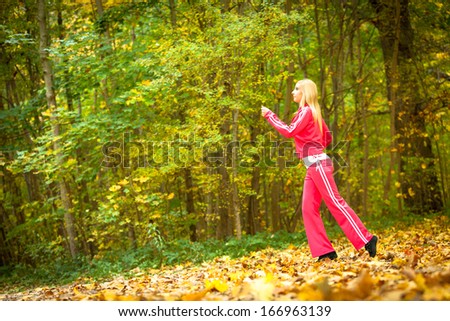 Woman running in autumn fall forest. Female runner training outdoor. Healthy lifestyle young blonde girl jogging outside. Yellow autumnal leaves.