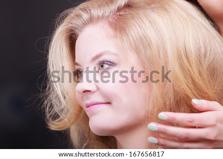 Beautiful smiling girl with blond wavy hair having her hair done. Young woman in hairdressing beauty salon. Hairstyle.