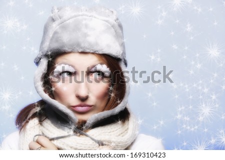 Fashion woman girl in warm clothing fur hat stylish creative make up false long white eye lashes on blue winter snow flakes background