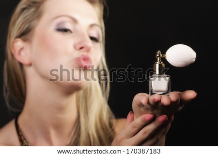 Sensuality concept. Portrait beautiful woman  kiss on lips with perfume bottle on black background