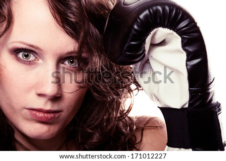 Martial arts or emancipation idea concept. Sport boxer woman in black gloves. Fitness girl training kick boxing showing her power domination. Isolated on white background.