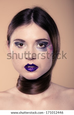 Portrait of girl young woman with long straight hair and creative makeup on brown. Studio shot.