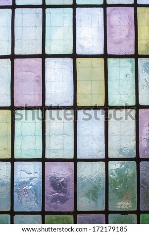 multicolored stained glass window with regular block pattern in hue of blue green violet