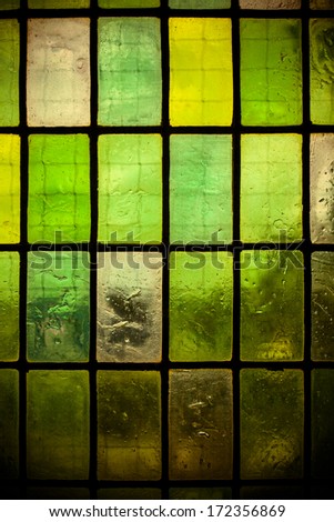 multicolored stained glass window with regular block pattern in hue of green