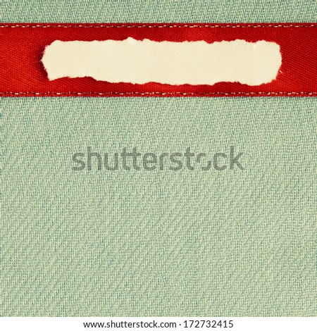 Piece scrap of white torn or ripped paper banner, blank copy space for text message red ribbon on green cloth background.