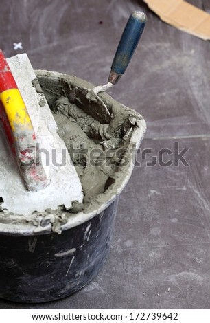 Construction worker is tiling at home, tile floor adhesive
