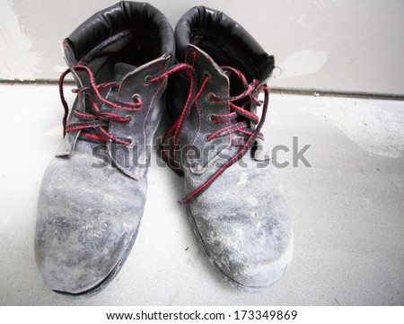 pair of old, dirty work boots at a construction site