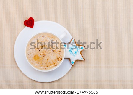 White cup of hot beverage drink coffee cappuccino latte with homemade gingerbread cake star with icing and blue decoration and red heart symbol love. Christmas. Holiday concept.