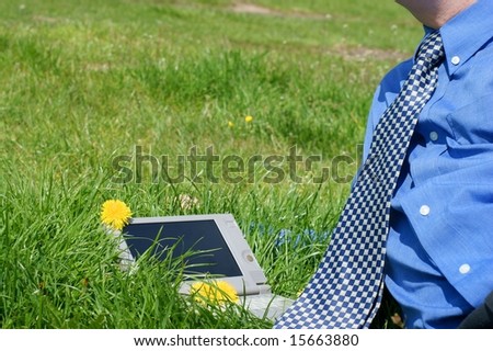 Businessman necktie and a laptop outside in a meadow
