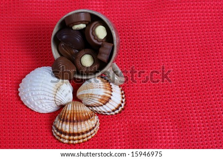 chocolate pralines candy, cup, shell red background. Delicious dark and milk chocolate pralines.