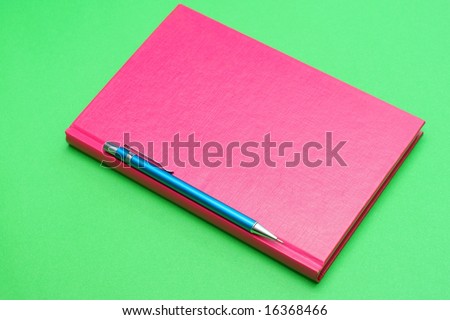 pencil and pink book on green background