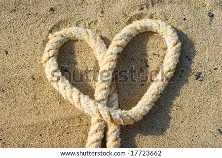 rope with a heart knot  - beach sand background