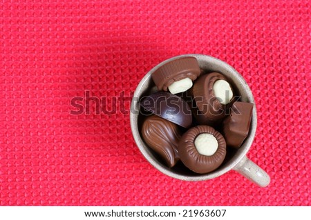 chocolate pralines candy, cup red background. Delicious dark and milk chocolate pralines.