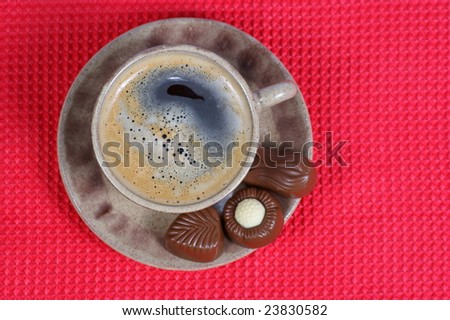 chocolate pralines cup with black coffee on red background. Delicious dark and milk chocolate pralines.