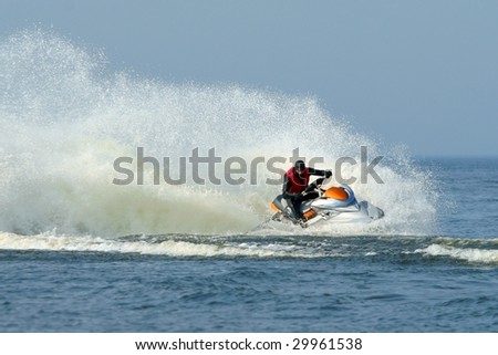 Backlit jet ski with water spray on the blue sea. Jetski in action, man on a jet-ski, making splashes.