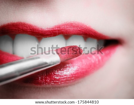 Part of woman face. Closeup of female red pink lips with makeup brush. Beautiful girl applying lipgloss lipstick. Beauty.