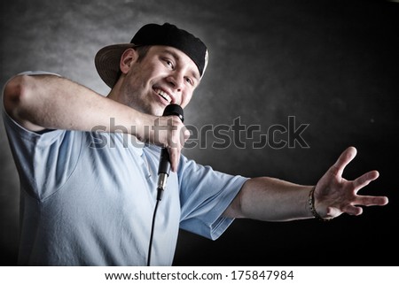 Rapper attitude rap singer hip Hop Dancer performing. Young man with microphone singing hand cool gesture black grunge background