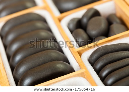 Beauty salon. Close up of black spa zen massage stones in wooden case as background. Relax concept.