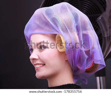 Portrait beautiful young woman in beauty salon. Blond girl with hair curlers rollers by hairdresser. Hairstyle.