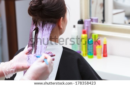 Professional female hairdresser applying color to female customer at design hair salon, woman having her hair dyed, Hair dye colouring in process