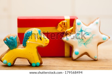 Homemade gingerbread cake pony and star with icing and colorful decoration and red gift box with golden ribbon. Christmas and holiday handmade concept.