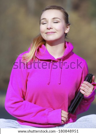 Fitness young woman sport teenage girl with close eyes in pink tracksuit holding tablet touchpad computer getting some sun on her face outdoor. Spring.