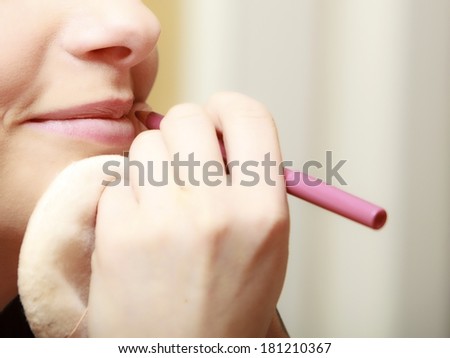 Female beauty. Makeup artist applying with pink pencil cosmetic on lips of her client young woman.
