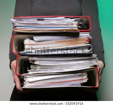 woman in grey holding stack of folders. Pile with old documents and bills on green background