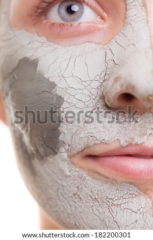 Skin care. Closeup of female face. Young woman applying clay green mud mask. Girl taking care of her dry compexion. Isolated. Spa and beauty treatment.