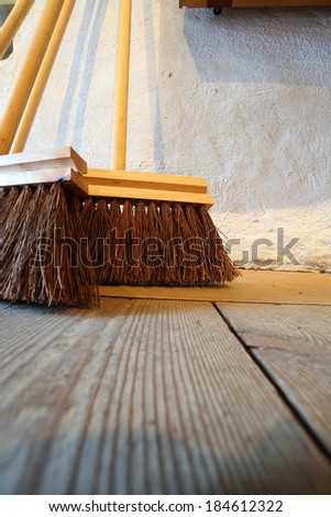 Close up large brooms for house work on old wooden floor of country house. Sweeping