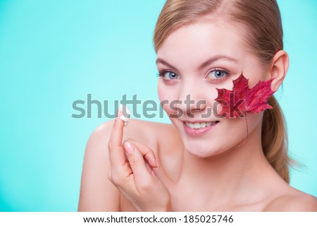 Skincare habits. Face of young woman with leaf as symbol of red capillary skin on turquoise. Girl taking care of her dry complexion applying moisturizing cream. Beauty treatment.