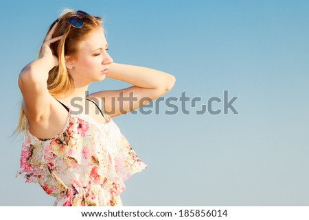 Vacation. Girl in summer dress standing alone on the empty beach. Young woman relaxing on the sea coast. Summertime.