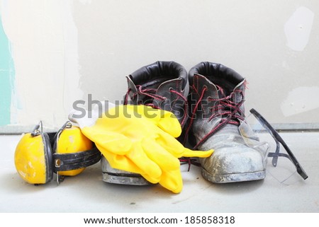 Renovation at home. Construction equipment tools work boots yellow protective noise muffs gloves glasses in building site.