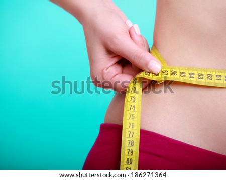 Time for diet slimming weight loss. Health care and healthy nutrition. Young fitness woman fit girl with measure tape measuring her waistline on blue green