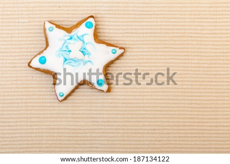 Homemade gingerbread cake star with icing and blue decoration on brown as christmas background. Holiday handmade concept.