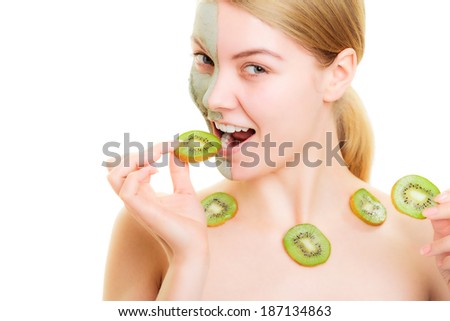 Skin care. Woman in clay mud mask on face and necklace with slices of kiwi eating fruit isolated. Girl taking care of dry complexion.