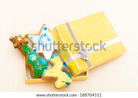 Christmas handmade gingerbread cakes with icing and decoration sweet dessert in golden gift box with silver ribbon on paper background. Holiday concept.