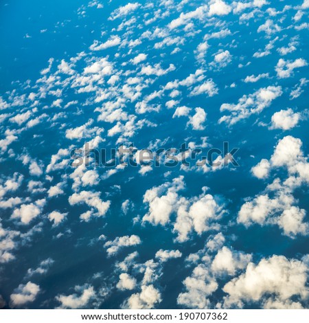 Blue sky. View from window of airplane flying in clouds. Skyscape cloudscape. Bird's eye.