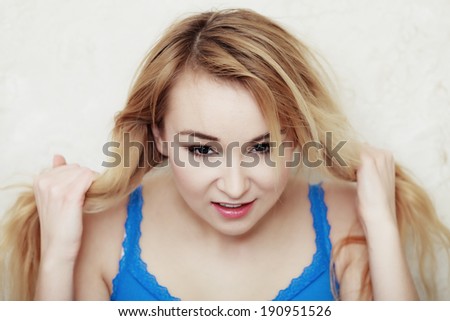 Hair problem. Blond woman teenage girl showing her damaged dry hair. Indoor.