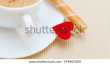 White cup of hot beverage drink coffee cappuccino latte with froth, sweet waffle roll stick with cream and red heart love symbol. Valentine\'s day. Studio shot.