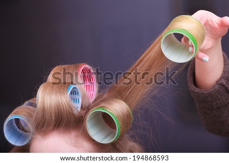 Part of woman. Blond girl with hair curlers rollers by hairdresser in hairdressing beauty salon. Hairstyle.