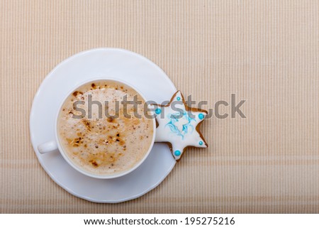 White cup of hot beverage drink coffee cappuccino latte and homemade gingerbread cake star with icing and blue decoration. Christmas. Holiday concept.