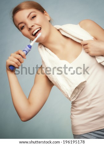 Young woman smiling girl with toothbrush brushing her white teeth on blue. Daily dental care. Studio shot.