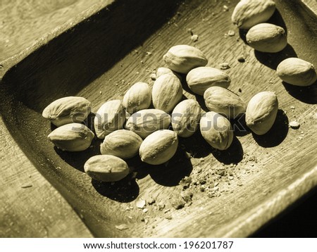 Salted snacks. Closeup of pistachios nuts in wooden bowl. Unhealthy food. Black-and-white photo.