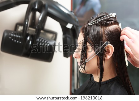 Hairstylist hairdresser combing hair of female client. Woman in hairdressing beauty salon.
