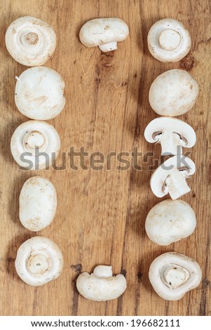 Vegetarian food. Frame of fresh white mushrooms champigonons on wooden kitchen table background.